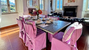 Un comedor con una mesa grande dispuesta para seis personas, rodeada de sillas tapizadas en rosa.