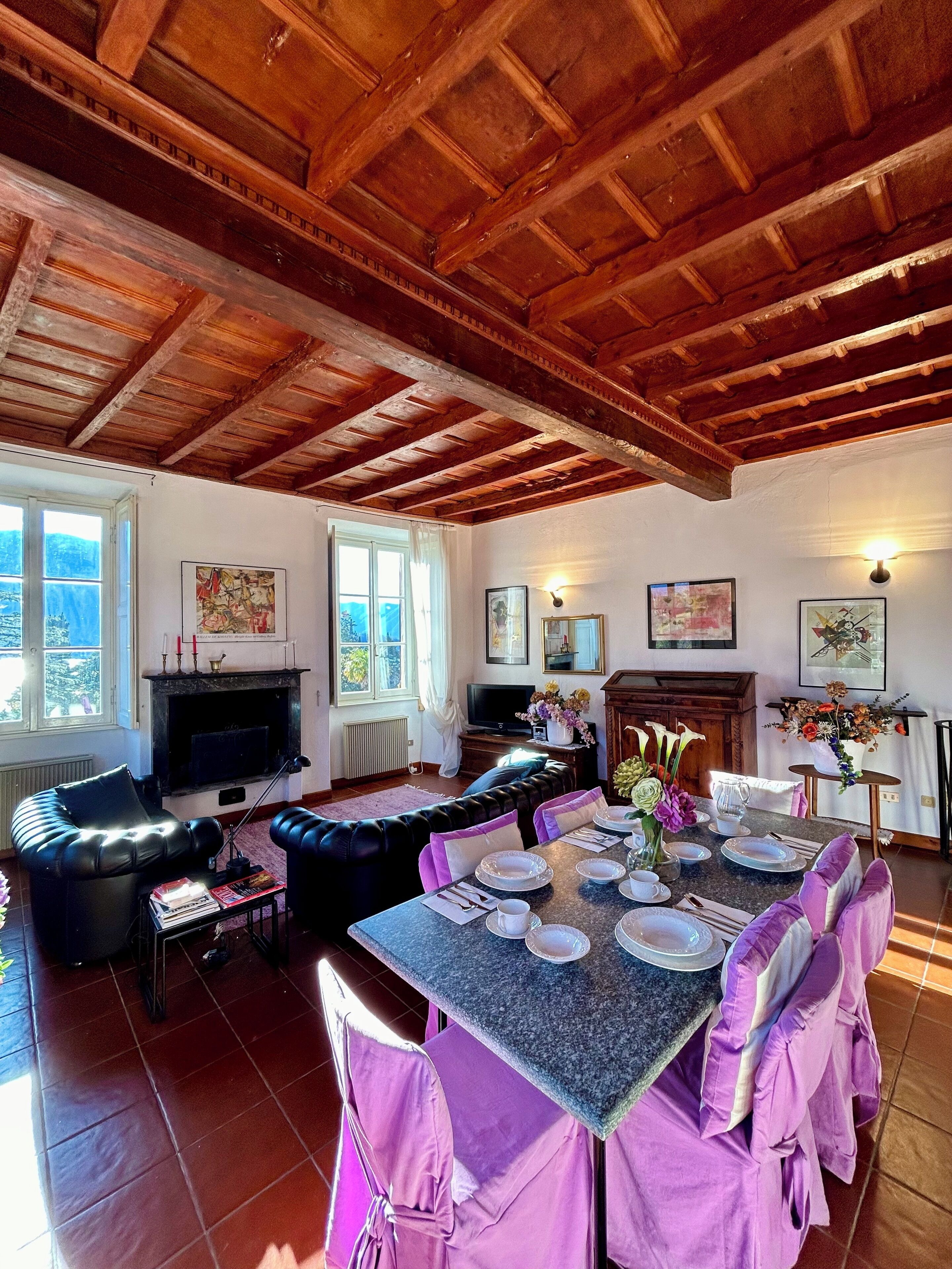 A dining area with a wooden ceiling, a fireplace, and a television.
