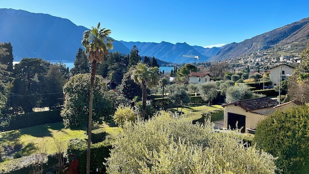 Vista panorámica de una zona montañosa con cielo despejado, abundante vegetación y una masa de agua al fondo.