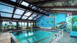 An indoor swimming pool with a view of the ocean, surrounded by a tropical mural, and a thatched roof structure. - Spacious Ocean Front Studio for 4 with Picture-Perfect View! (Daytona Beach Shores)
