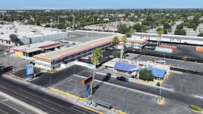 Vista aèria d'una zona comercial amb una benzinera, un aparcament i un magatzem de contenidors.
