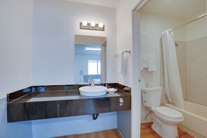 A bathroom with a sink, mirror, and a shower area.