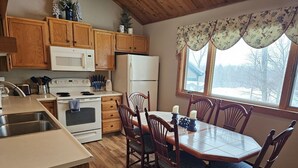 Une cuisine avec des meubles de rangement en bois, un four à micro-ondes, une cuisinière, un réfrigérateur et une table à manger avec des chaises.