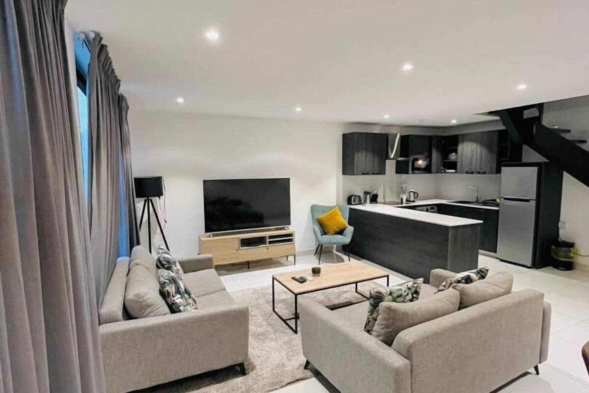 Una sala de estar moderna con sofá, mesa de centro y televisor.