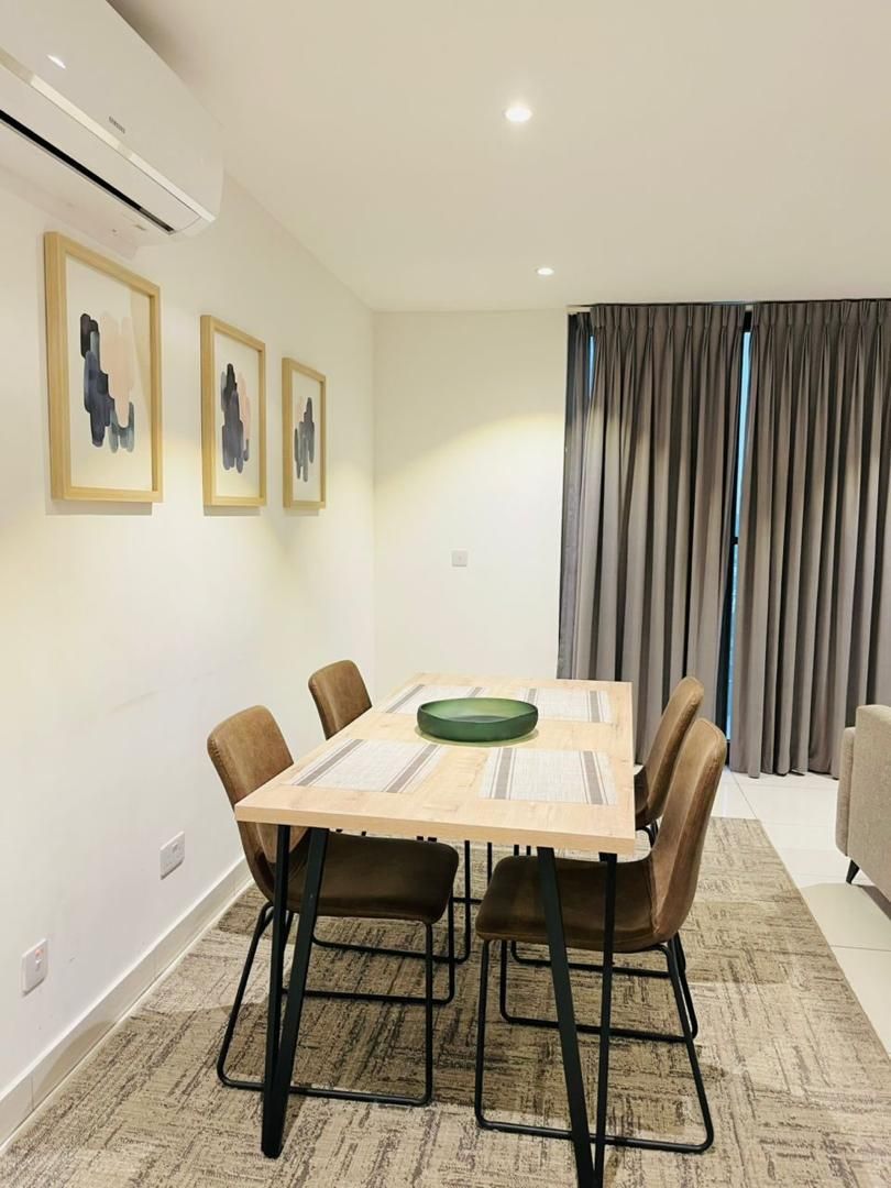 A dining area with a wooden table, four chairs, and a green plate.