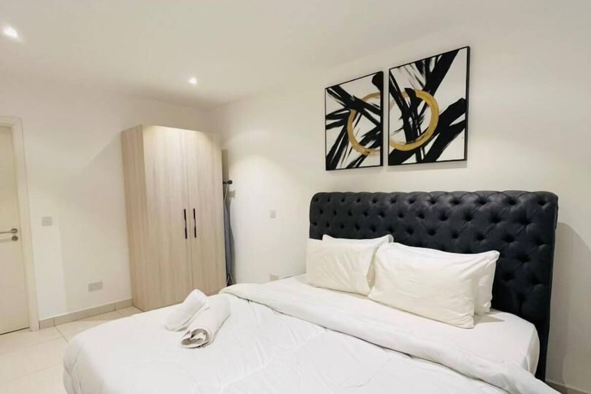 Un dormitorio con una cama grande, un armario y dos obras de arte abstractas en la pared.