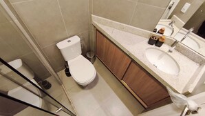 A bathroom with a toilet, sink, and mirror. - Flats Garden no Nomar Carneiros Ecoloving (Tamandaré)