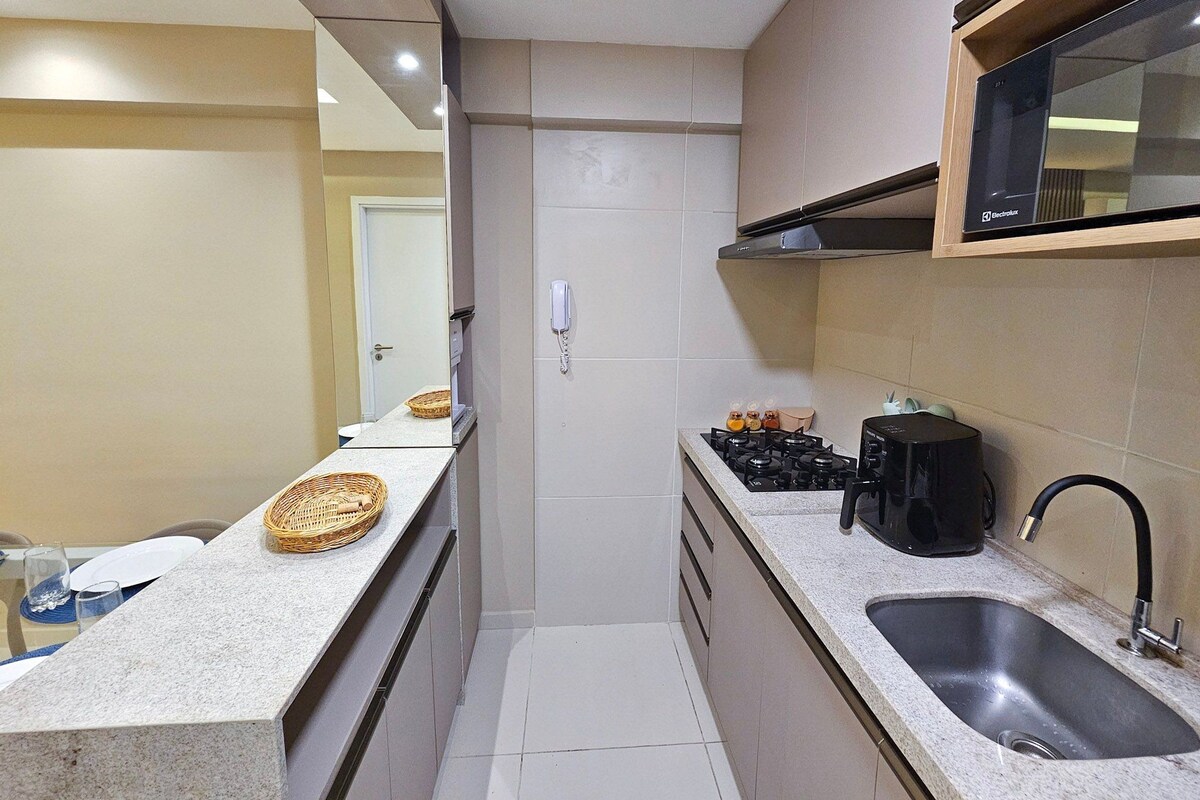 A compact kitchen with a microwave, stove, and sink.