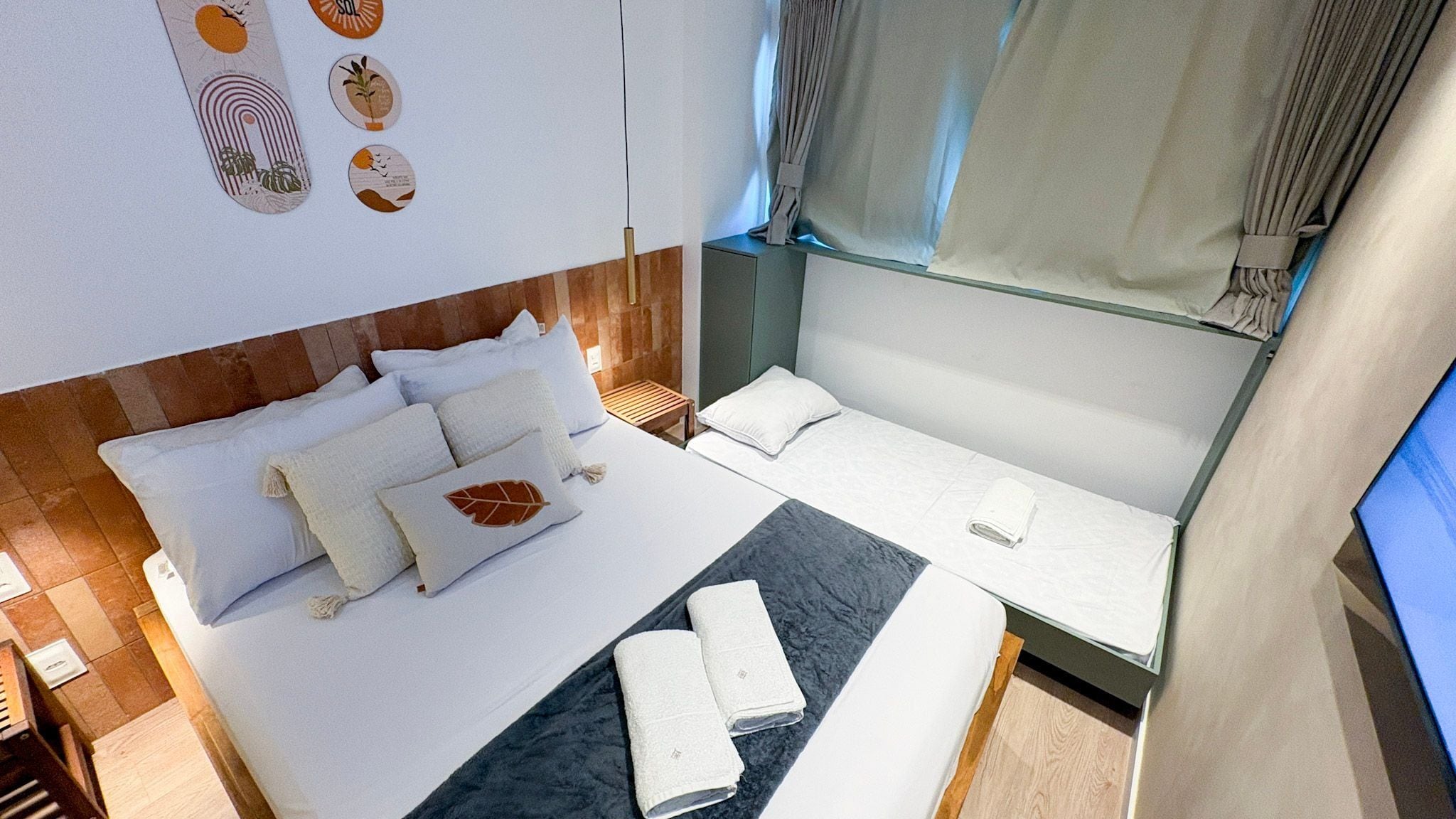 A compact hotel room with a bed, a small seating area, and a window with curtains.