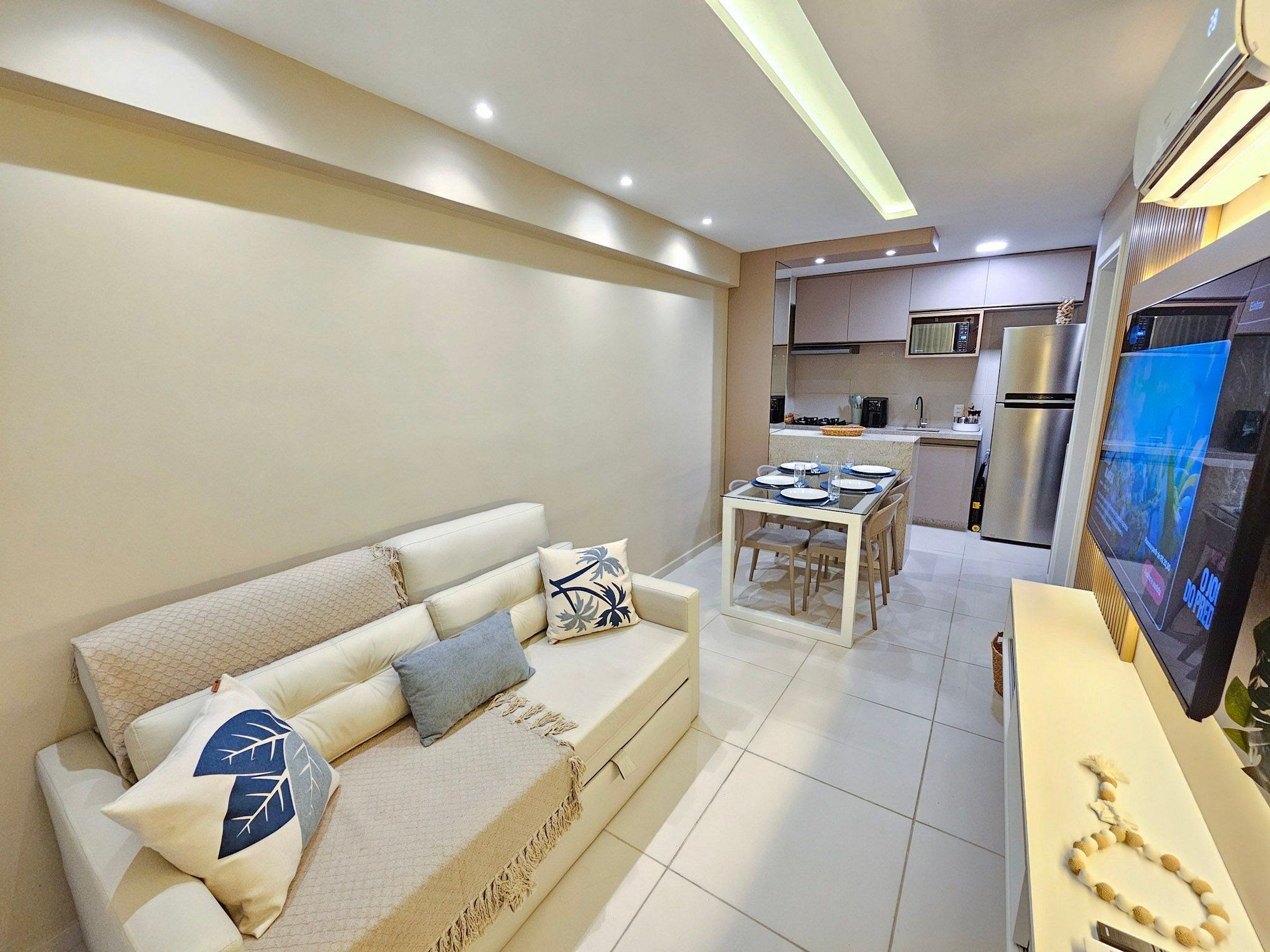 A modern living room with a sofa, a dining table, and a kitchen area in the background.