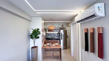 A narrow hallway with a dining area, a kitchen, and an air conditioning unit.