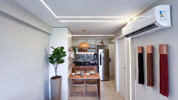 A narrow hallway with a dining area, a kitchen, and an air conditioning unit.