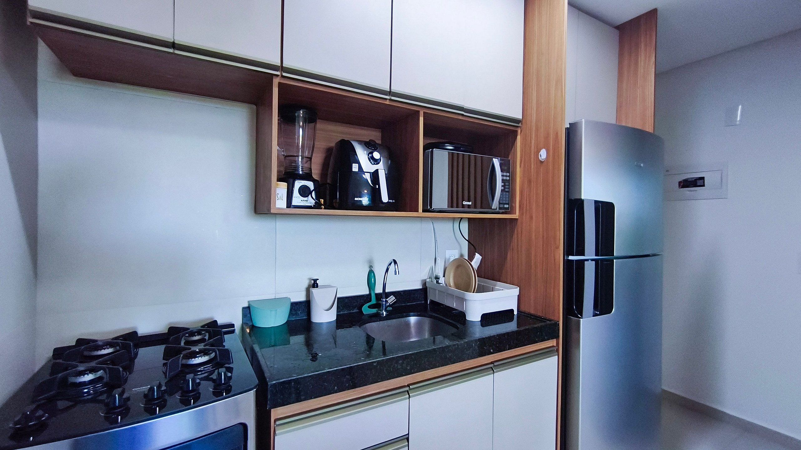 A compact kitchen with a gas stove, a sink, a microwave, and a refrigerator.