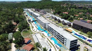A resort with multiple swimming pools, a large building with balconies, and a surrounding landscape with trees. - Galapagos Beach Residence - Praia dos Carneiros (Tamandaré)