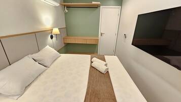 A hotel room with a bed, a TV, a wardrobe, and a small seating area.