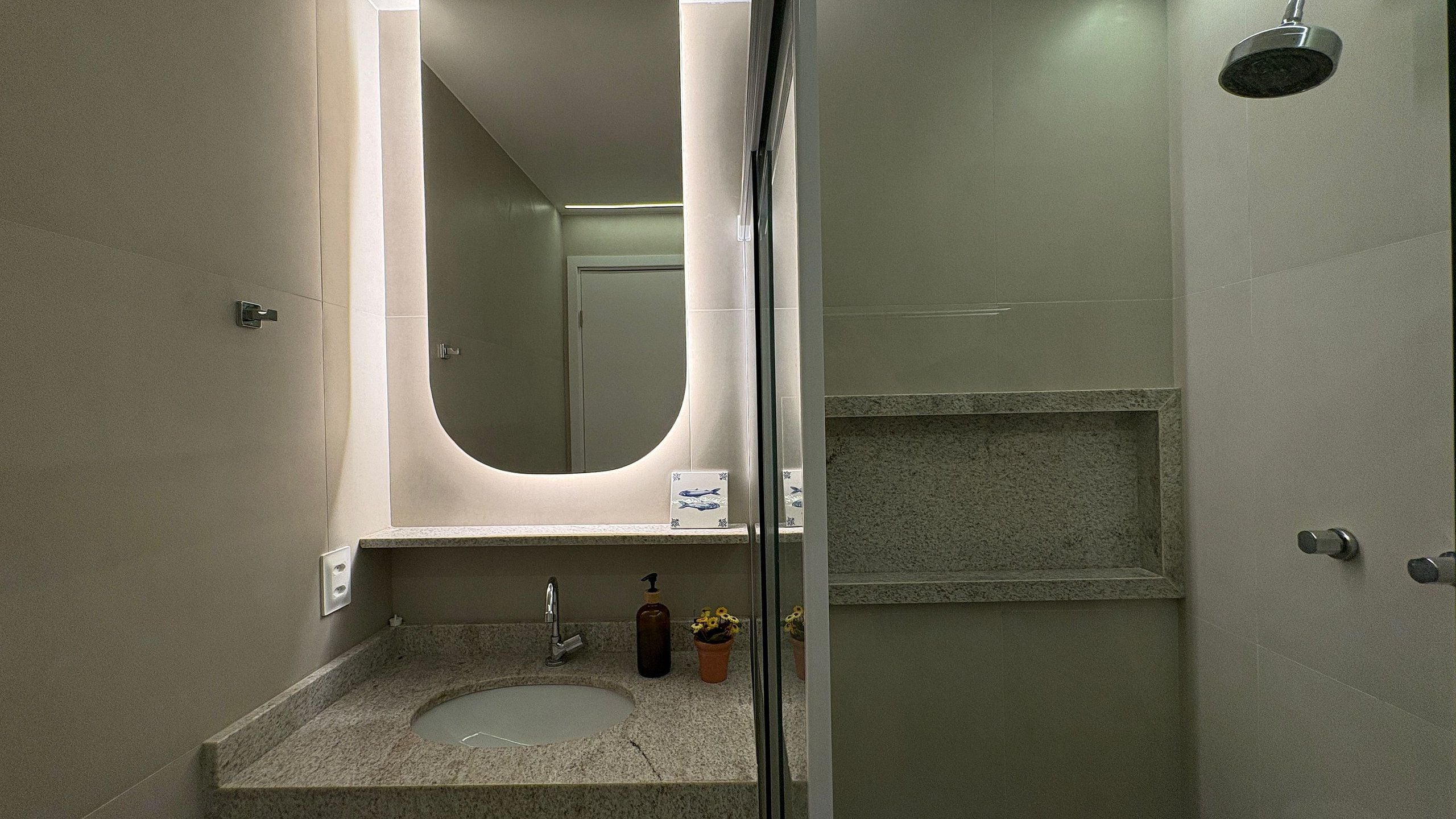 A bathroom with a granite countertop sink, a mirror, a shower with a glass door, and a towel rack.