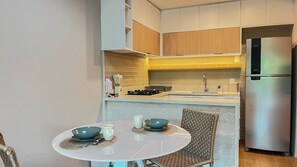 A compact kitchen with a built-in refrigerator, a sink, and a dining table with two bowls and cups. - Galapagos Beach Residence - Praia dos Carneiros (Tamandaré)