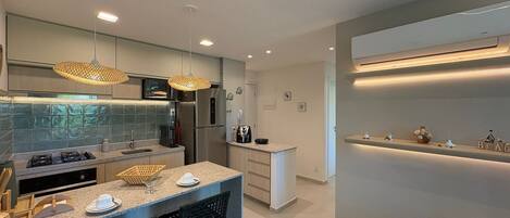 A modern kitchen with a central island, stainless steel appliances, and pendant lighting.