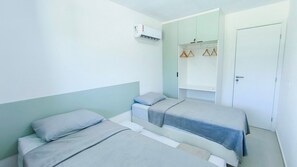Een kamer met twee bedden, een garderobe en een airconditioning.