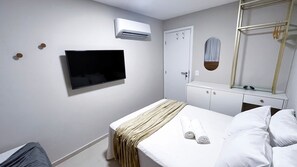 A hotel room with a bed, a TV, a wardrobe, a mirror, and an air conditioning unit. - Galapagos Beach Residence - Praia dos Carneiros (Tamandaré)