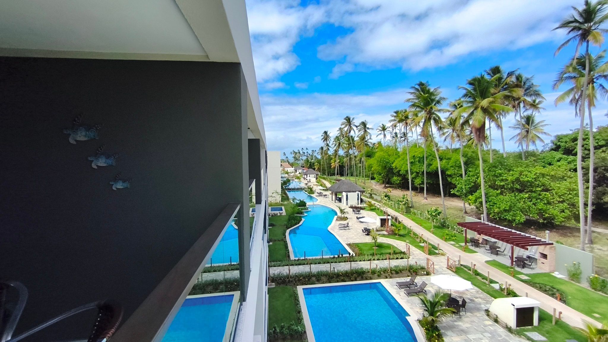 Ein Resort mit mehreren Swimmingpools, Palmen und blauem Himmel.