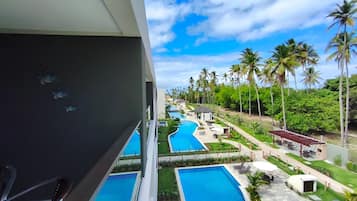 A resort with multiple swimming pools, palm trees, and a clear sky.
