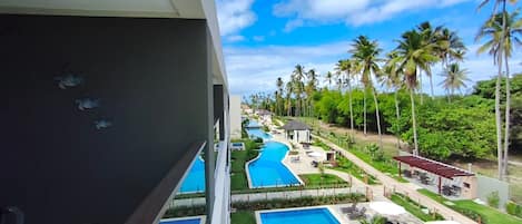 Un resort con varias piscinas, palmeras y cielo despejado.