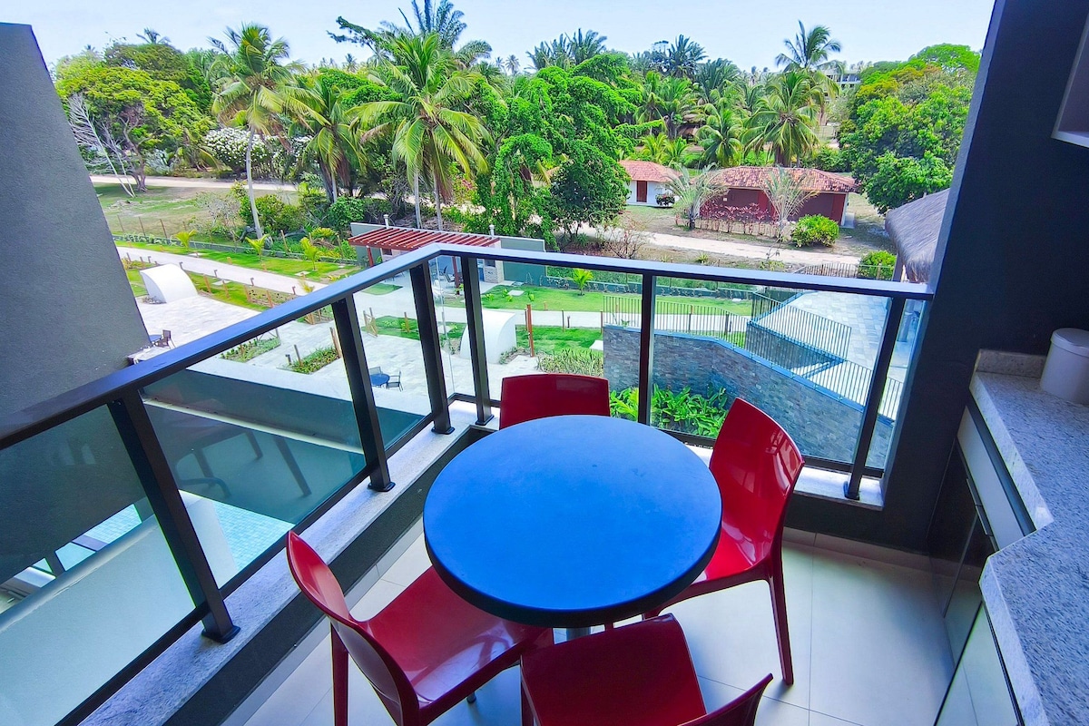 A balcony with a glass railing, a round table, and red chairs.