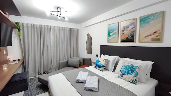 A modern hotel room with a bed, a desk, and a large window with curtains. - Galapagos Beach Residence - Praia dos Carneiros (Tamandaré)