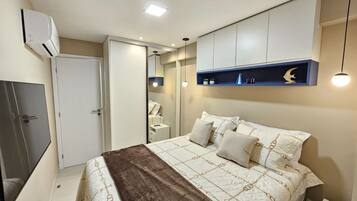 Een slaapkamer met een bed, nachtkastje, garderobe en ingebouwde kasten.