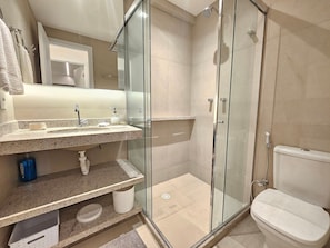 Ein modernes Badezimmer mit einer Duschkabine aus Glas, einem Waschbecken mit Marmorplatte und einer Toilette.