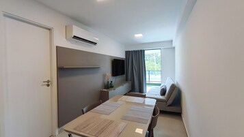 Una habitación moderna con una mesa de comedor, sillas, un sofá, un televisor de pantalla plana y un equipo de aire acondicionado.