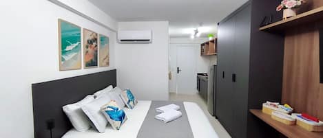 Une chambre d’hôtel comprenant un lit, une table de chevet, une armoire, un petit coin cuisine et des œuvres d’art murales.