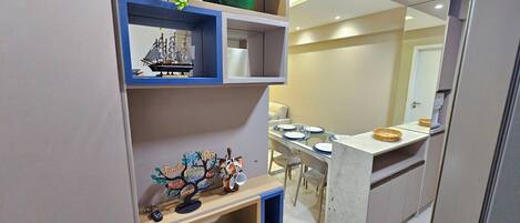 A modern kitchen with built-in shelves, a dining area with a table set for two, and a refrigerator.