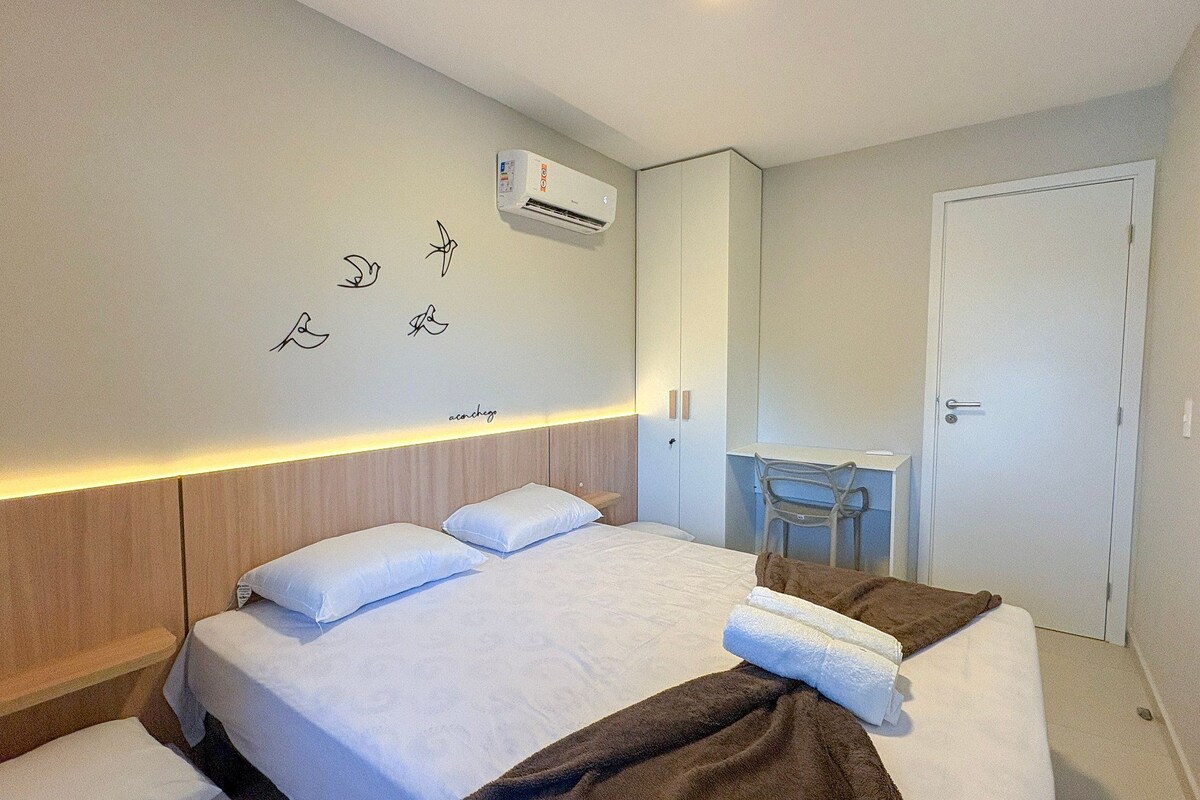 A hotel room with a bed, bedside table, and a mirror.