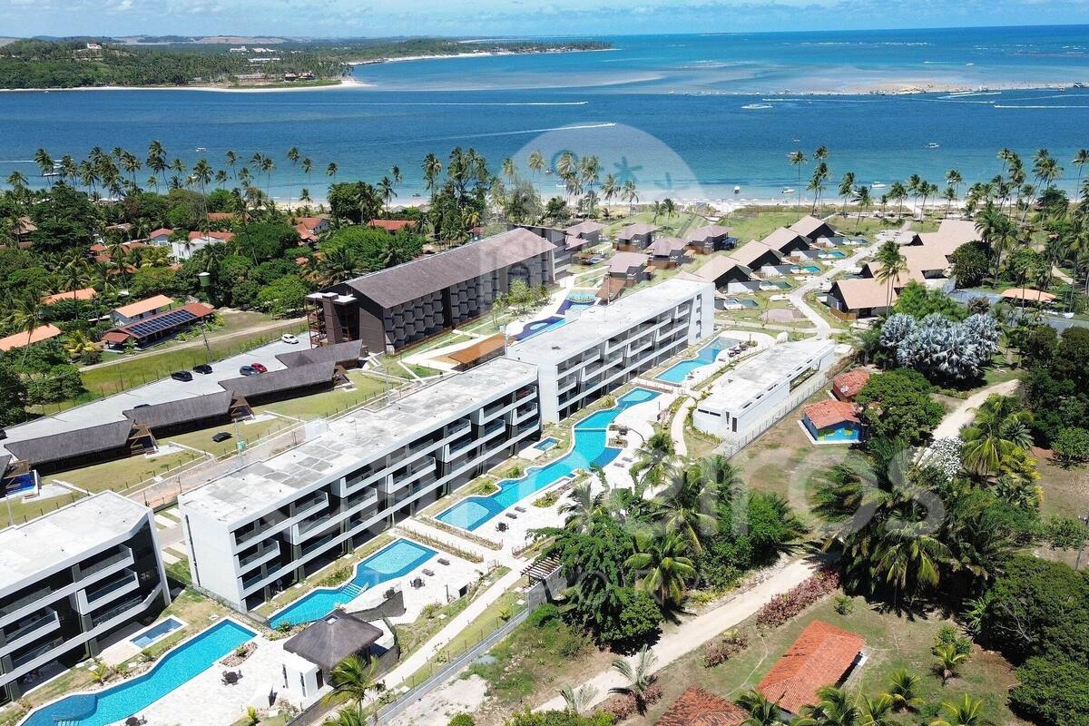 Un resort con varias piscinas, un edificio grande y vista al océano.