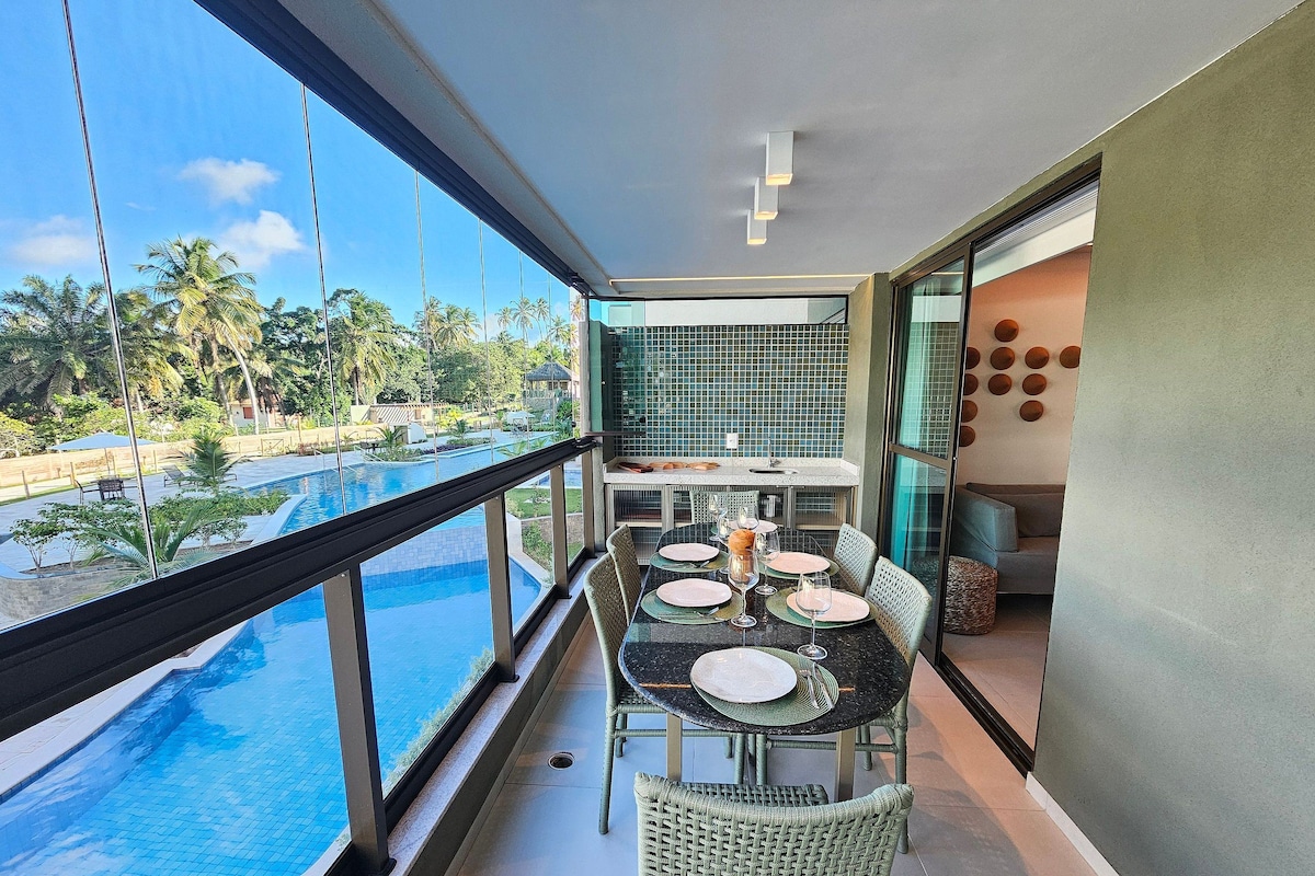 A balcony with a pool view, a dining table with chairs, and a kitchen area.