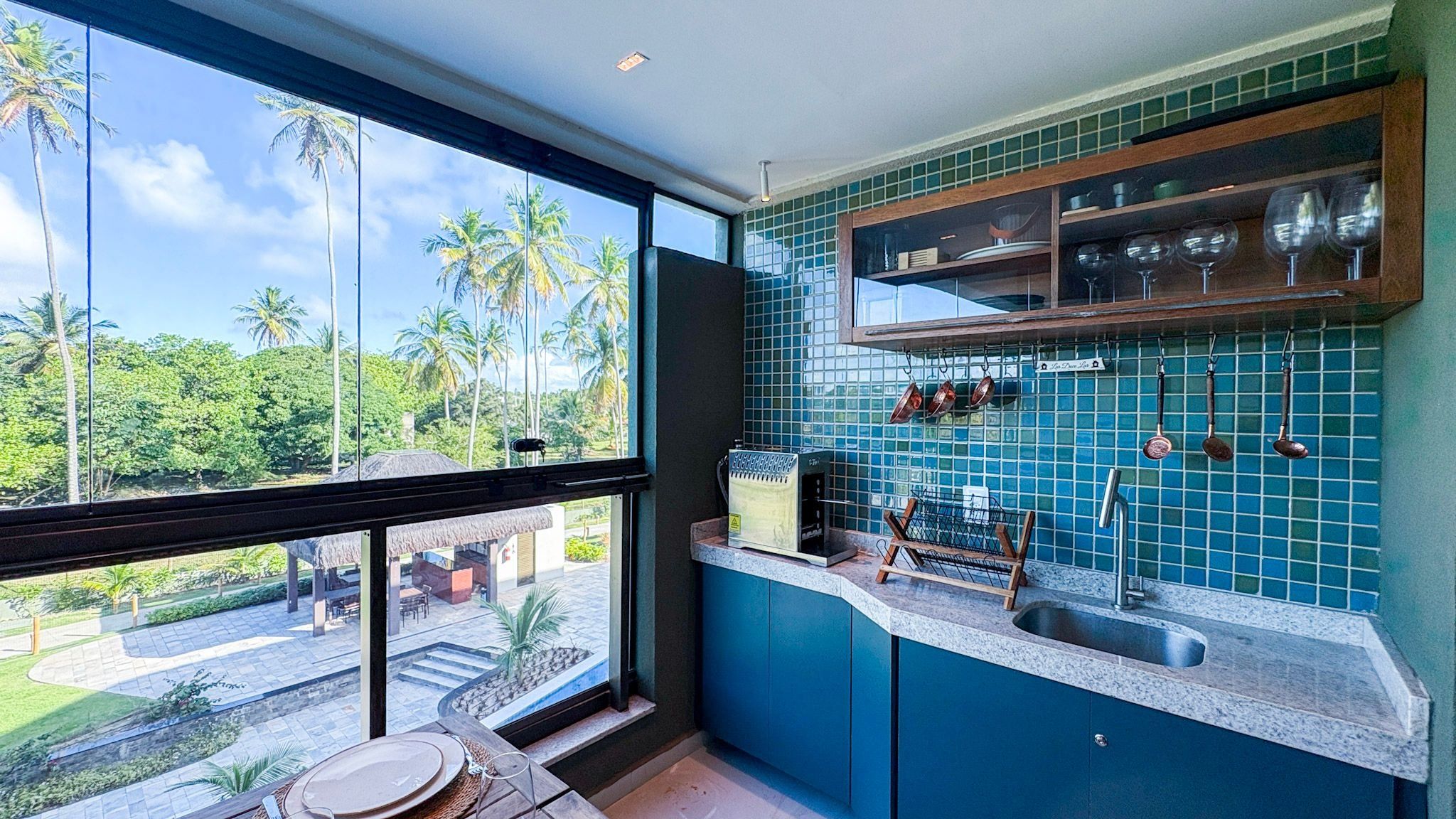 Cozinha com vista para palmeiras e piscina.