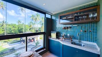 Cozinha com vista para palmeiras e piscina.
