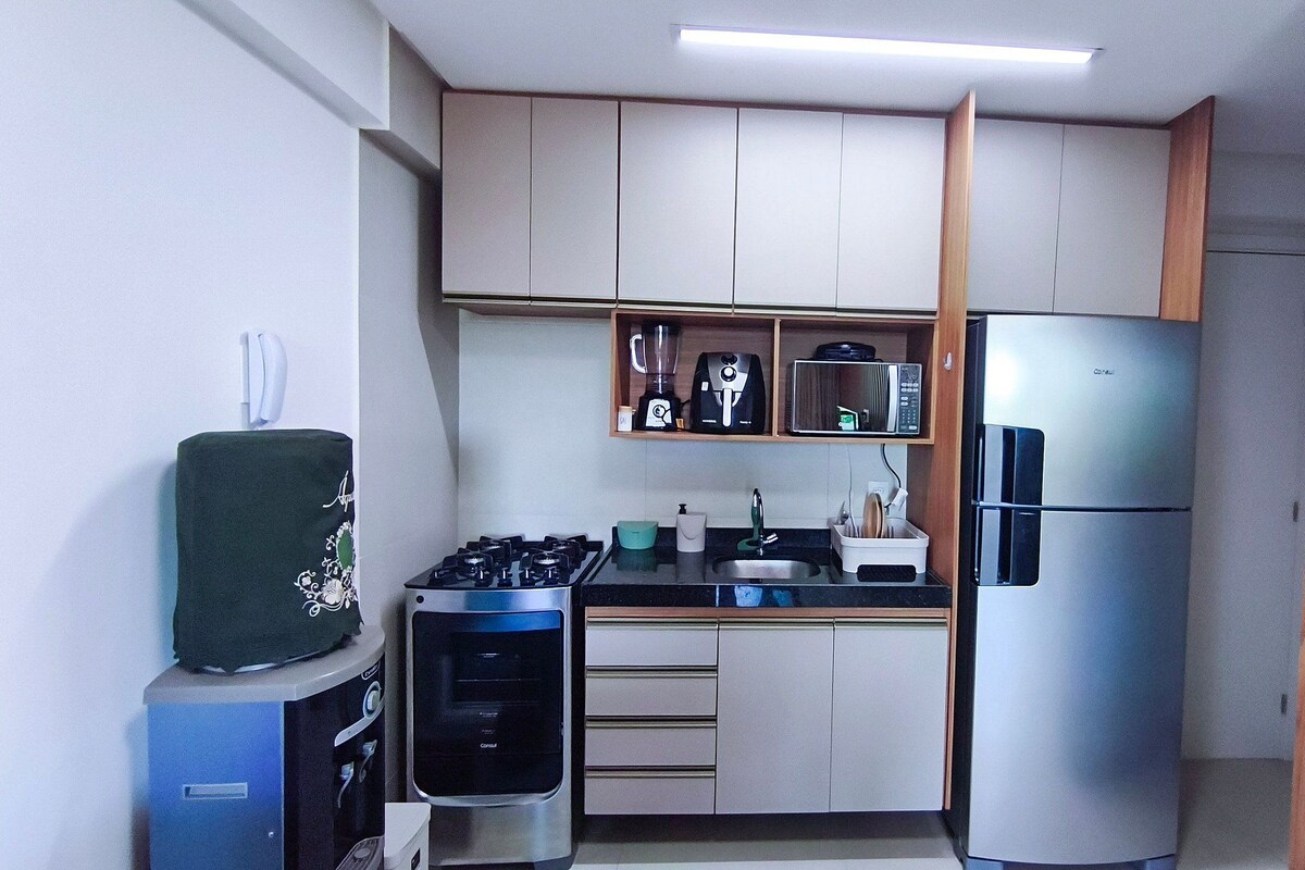 Cocina compacta con estufa a gas, microondas, refrigerador y pileta.