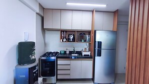 A compact kitchen with a gas stove, a microwave, a refrigerator, and a sink. - Galapagos Beach Residence - Praia dos Carneiros (Tamandaré)