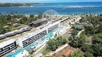 Un resort con varias piscinas, un edificio grande y vista al océano.