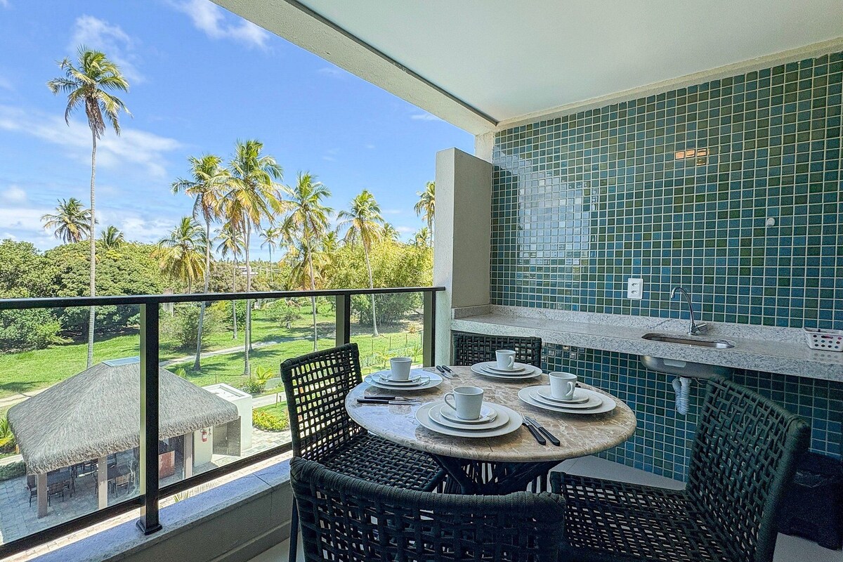 A balcony with a table set for two, overlooking a lush landscape with palm trees.