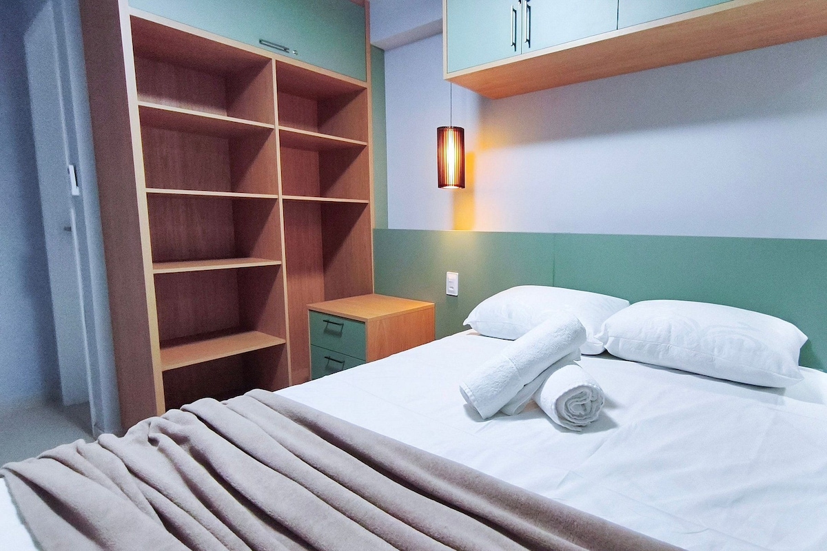 Ein Hotelzimmer mit einem Bett, einem Nachttisch, einem Kleiderschrank und einer Wandlampe.
