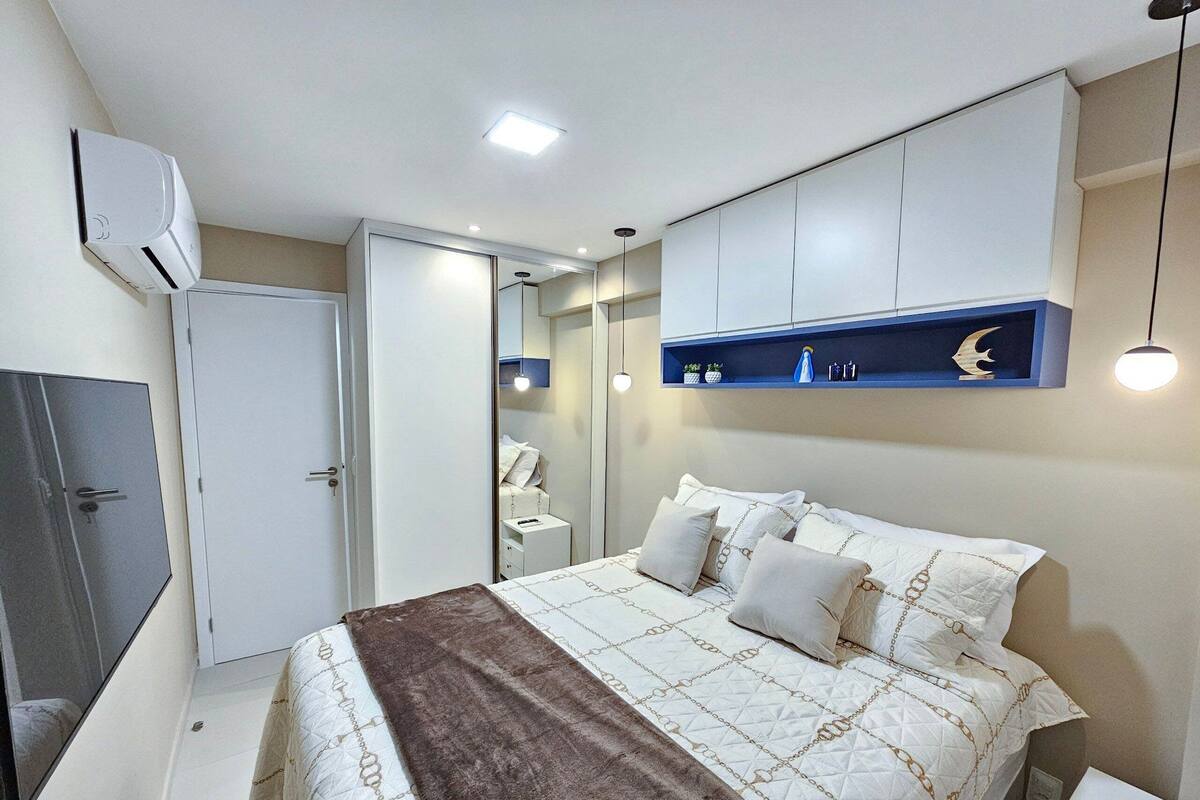 Ein Schlafzimmer mit Bett, Nachttischen, einem Kleiderschrank, einem Spiegel und einem Regal mit Dekoration.