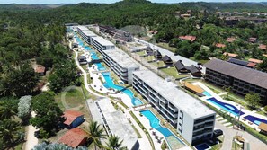 A resort with multiple swimming pools, a large building with balconies, and a lush green environment.