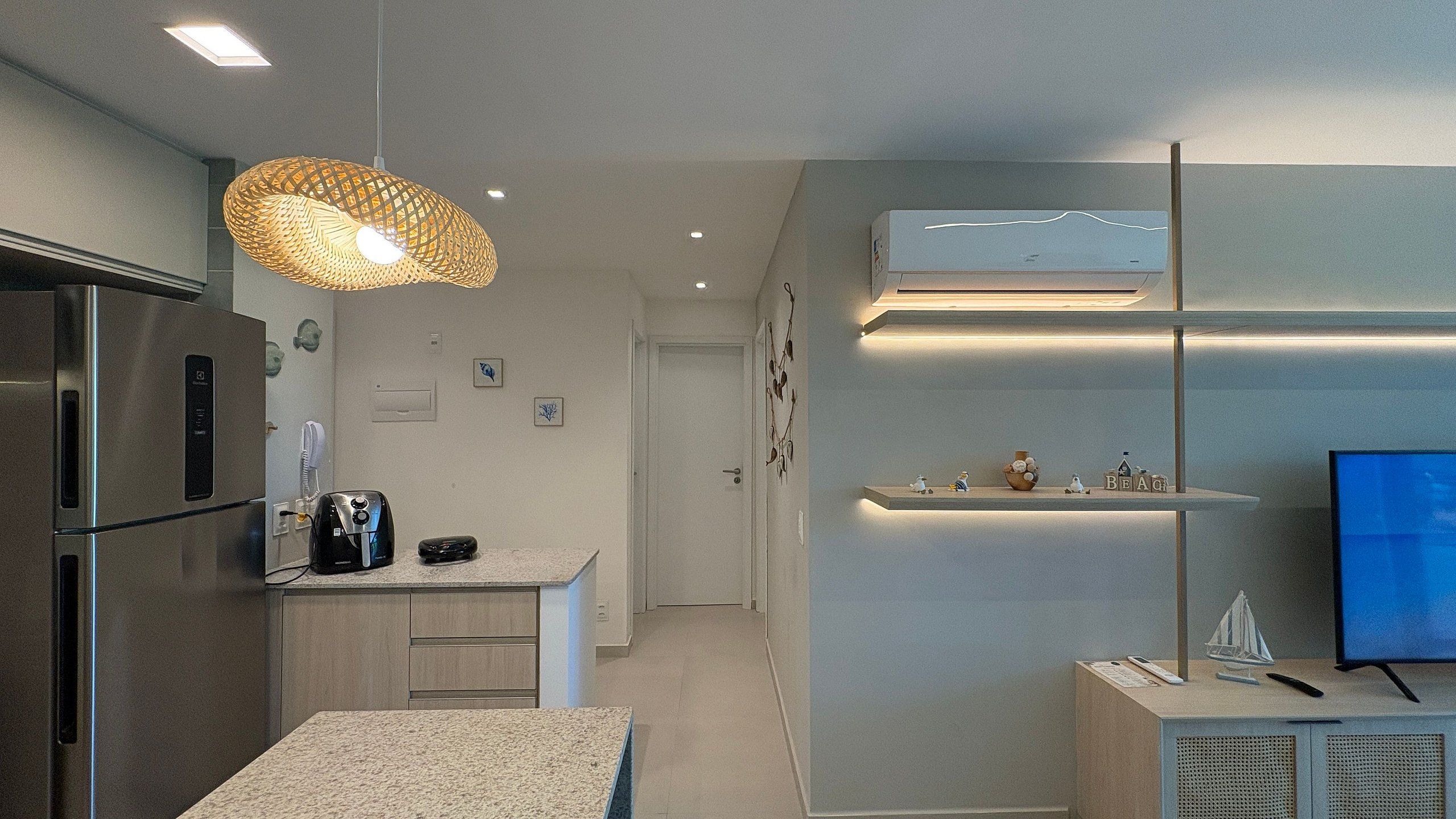 Cozinha moderna com geladeira embutida, cafeteira e luminária pendente.