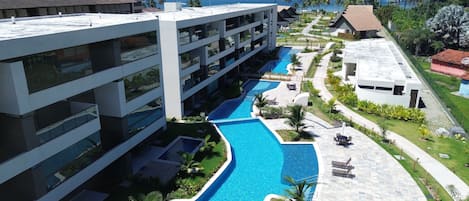 A resort with a swimming pool, multiple buildings, and a view of the ocean.