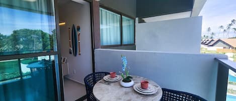 A balcony with a table and chairs, a potted plant, and a view of the surrounding area.