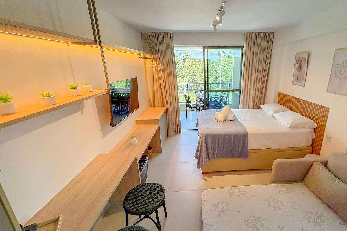 Ein Hotelzimmer mit Bett, Schreibtisch, Sessel, Sofa und Fernseher.